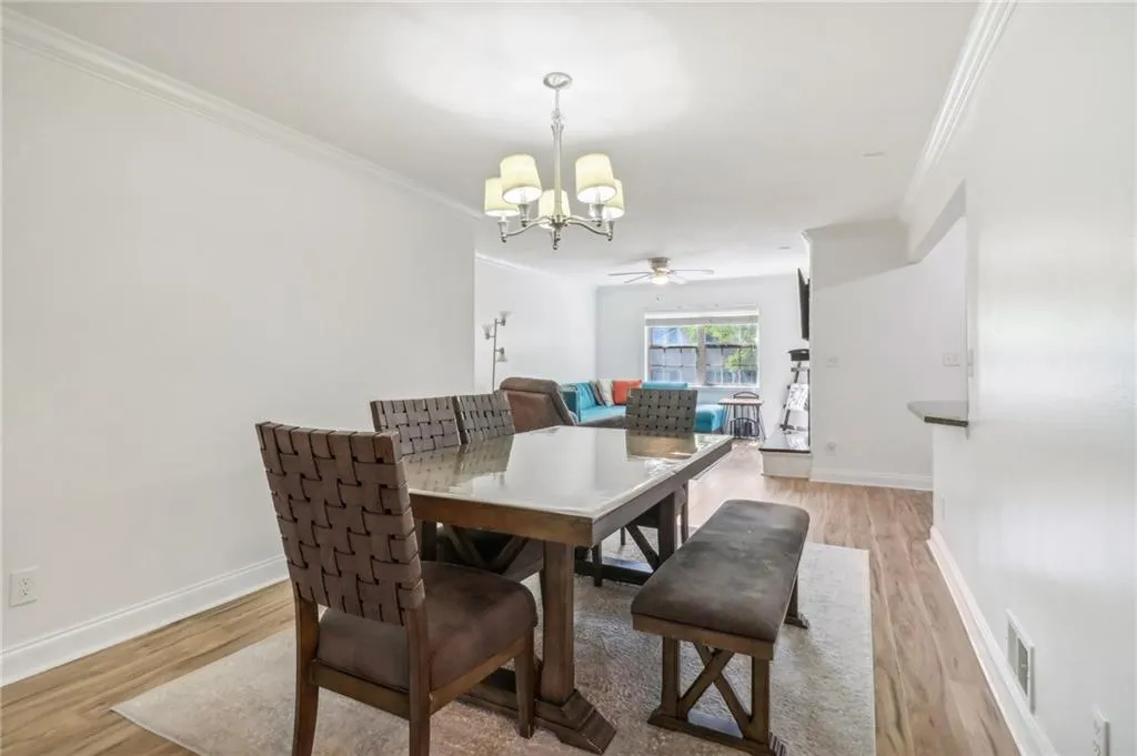 Dining area featuring ornamental molding, ceiling fan with notable chandelier, and light wood-type flooring Dining area featuring ornamental molding, ceiling fan with notable chandelier, and light wood-type flooring