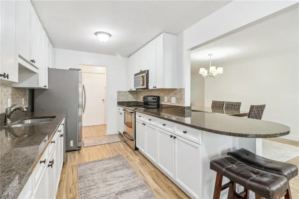 Kitchen with decorative backsplash, appliances with stainless steel finishes, light wood-type flooring, and a breakfast bar area Kitchen with decorative backsplash, appliances with stainless steel finishes, light wood-type flooring, and a breakfast bar area