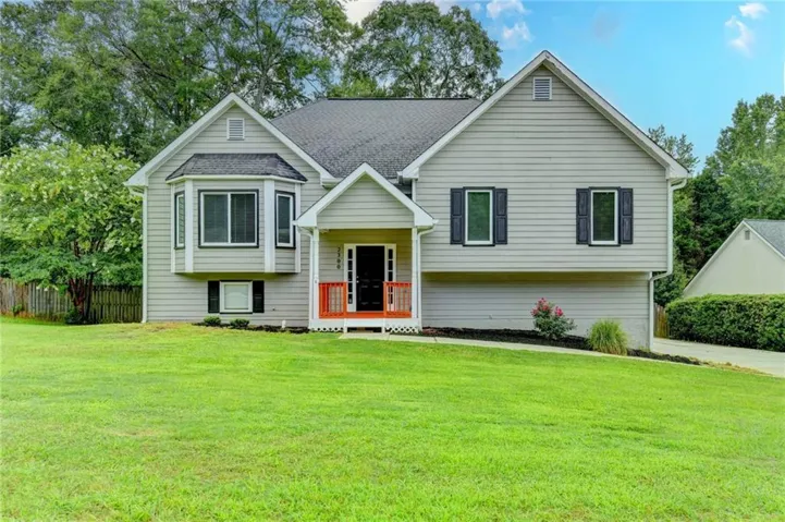 Traditional-style home featuring light gray siding with white trim, a covered front entry with red railings, a prominent bay window, and dark window shutters