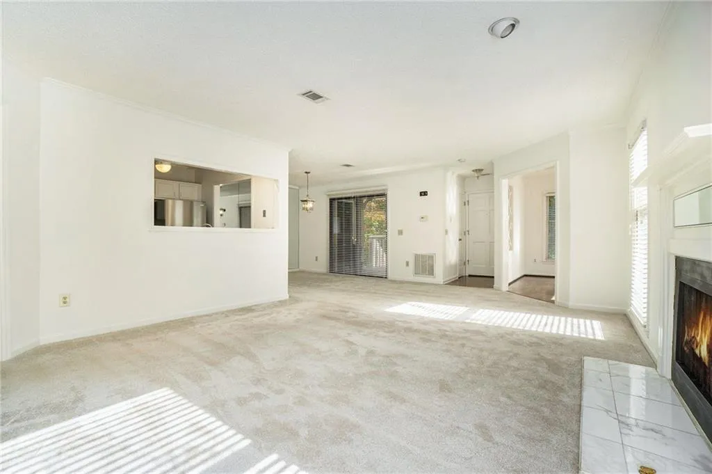 Unfurnished living room with light colored carpet and crown molding