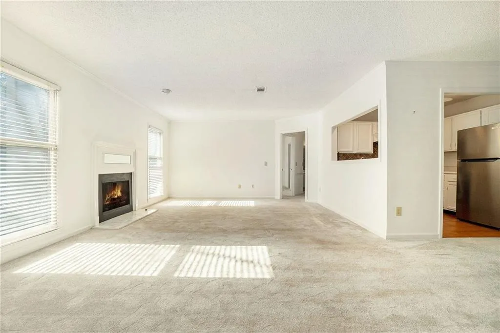 Unfurnished living room featuring light carpet, plenty of natural light, and a textured ceiling