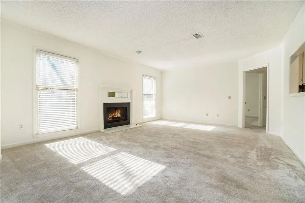 Unfurnished living room with light carpet, a textured ceiling, and ornamental molding