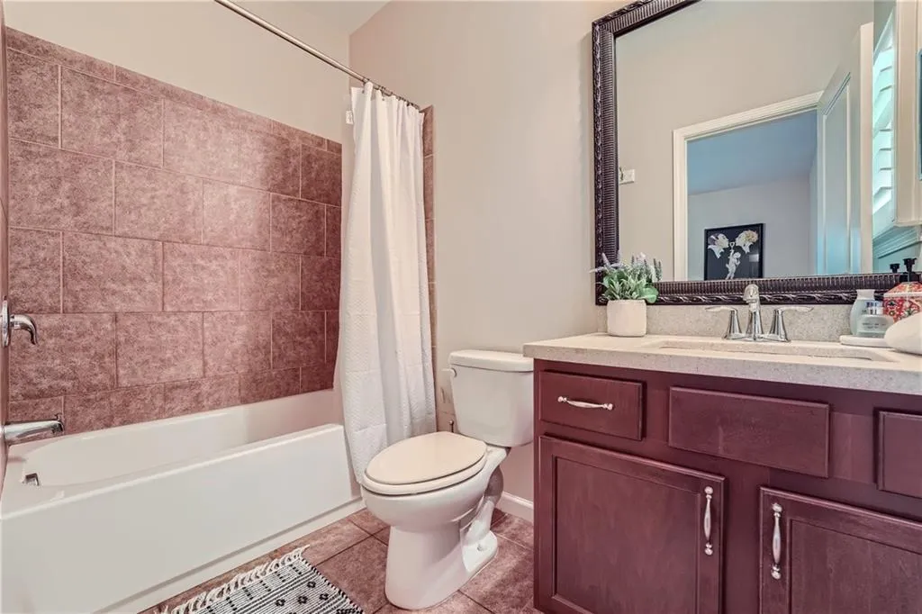 Full bathroom with toilet, shower / tub combo, vanity with extensive cabinet space, and tile flooring