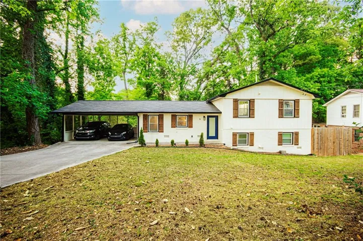 White exterior with dark wood shutters, a dark blue entry door, and a covered carport