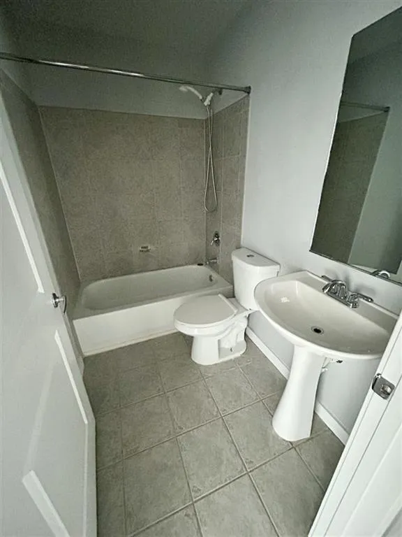 Bathroom featuring a pedestal sink, ceramic tile flooring, and a shower with tiled surround