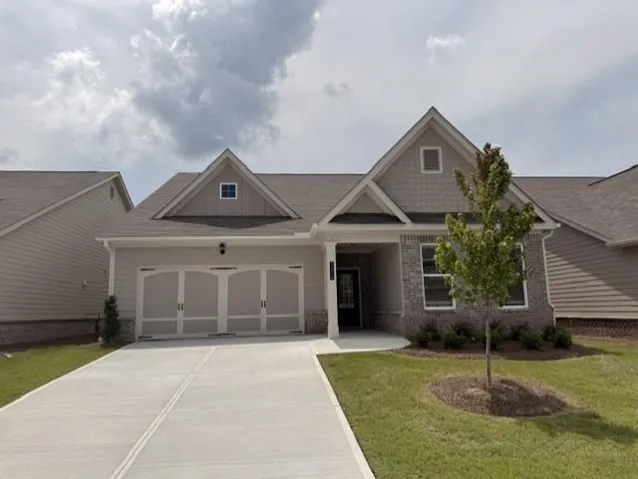 Contemporary ranch-style residence featuring a two-car garage, partial brick facade, and gabled rooflines