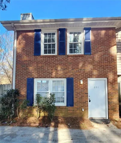 Brick exterior with blue louvered shutters, white window frames, and a white entry door