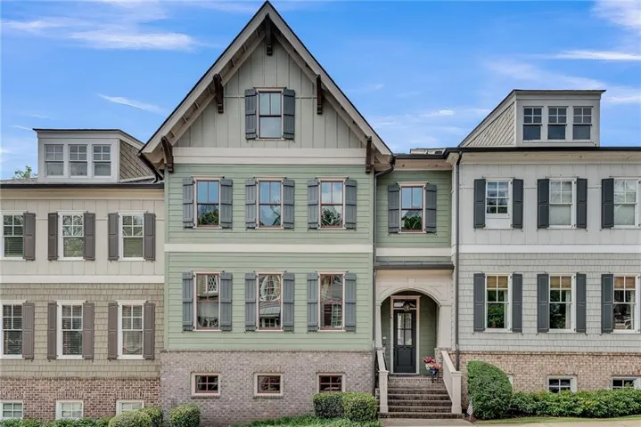 Multi-level exterior with dormer windows, shuttered windows, a gabled roofline, brick foundation, and a central entryway with steps