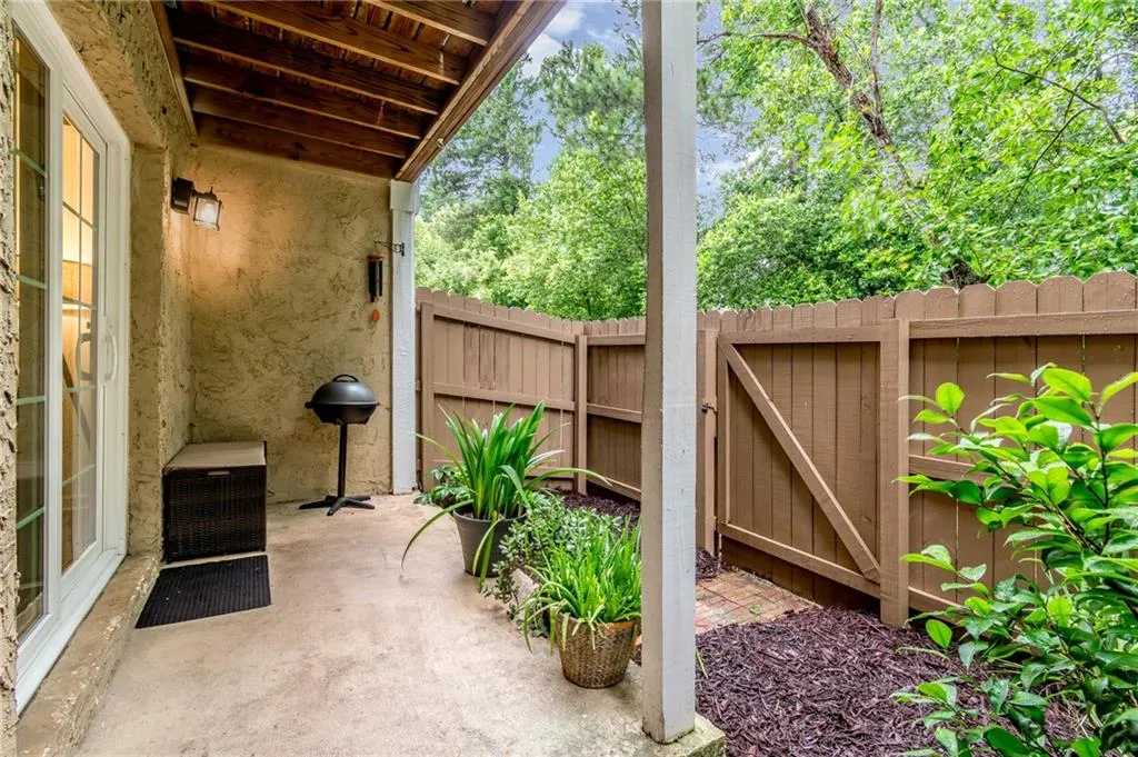 Covered fenced patio with a wood beam ceiling, and concrete flooring