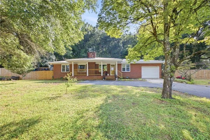 Brick exterior residence with an attached garage, covered front porch, and a paved driveway