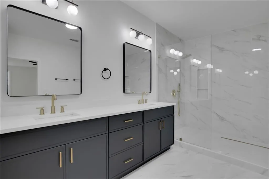 Full bath with light marble finish flooring, double vanity, and a marble finish shower