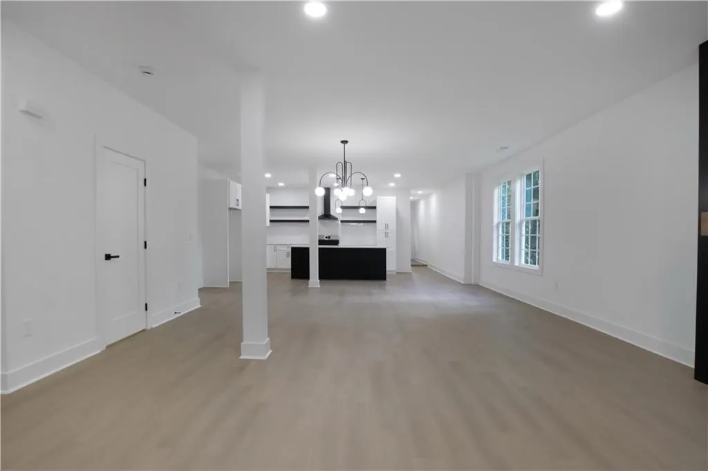 Unfurnished living room with light wood finished floors, recessed lighting, and a chandelier