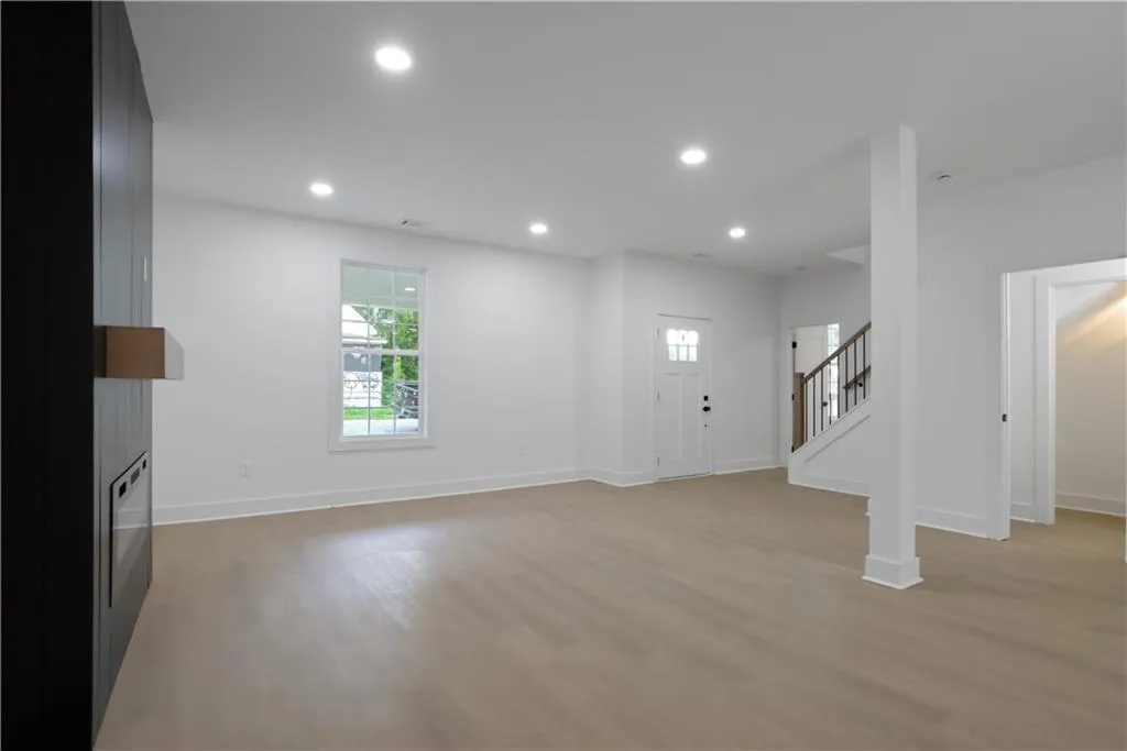 Unfurnished living room featuring stairway, light wood-style flooring, and recessed lighting