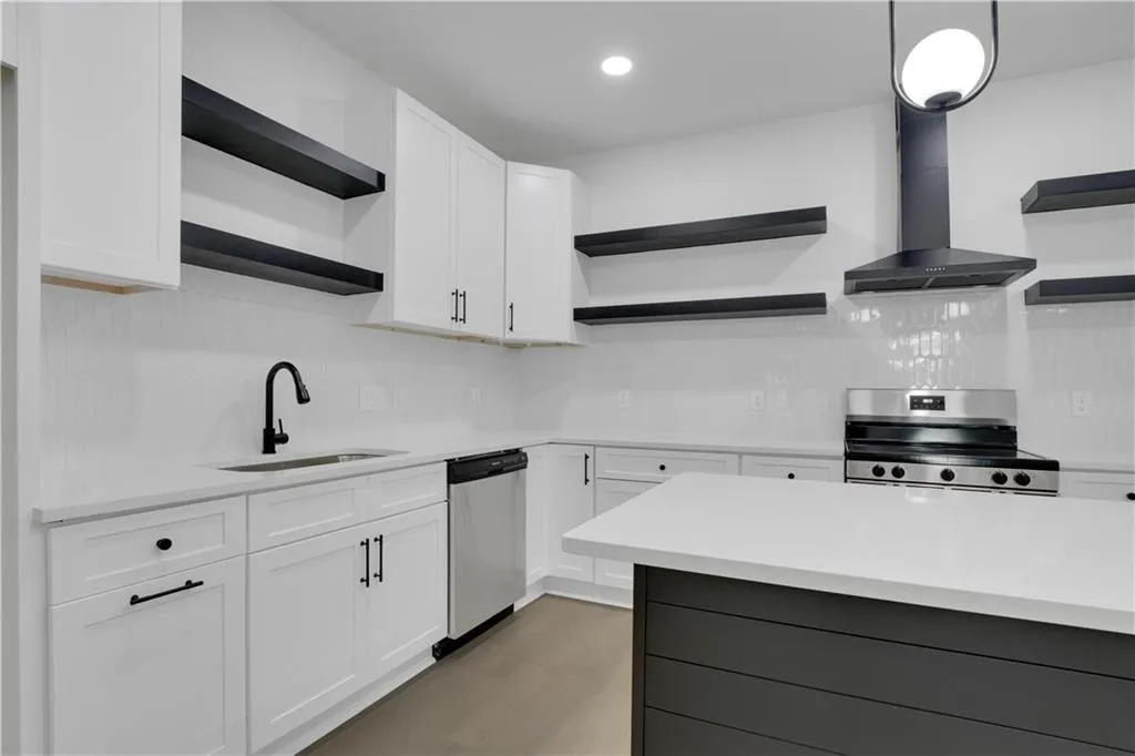 Kitchen featuring open shelves, white cabinets, wall chimney exhaust hood, appliances with stainless steel finishes, and recessed lighting