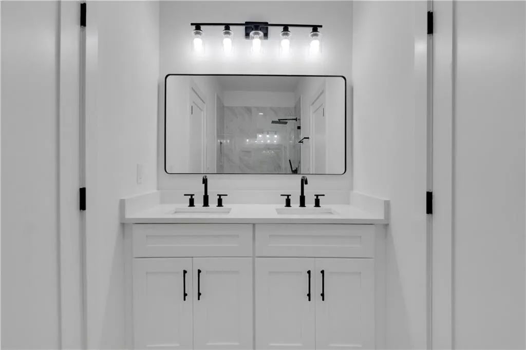 Bathroom featuring a marble finish shower and double vanity