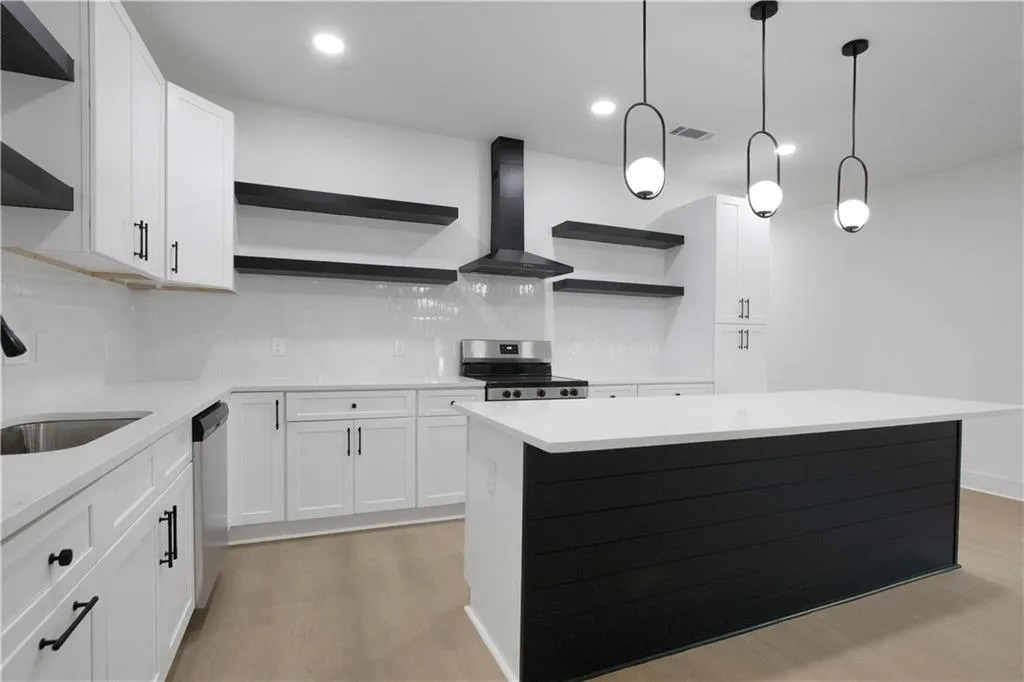 Kitchen with open shelves, white cabinets, decorative backsplash, wall chimney range hood, and light wood-type flooring