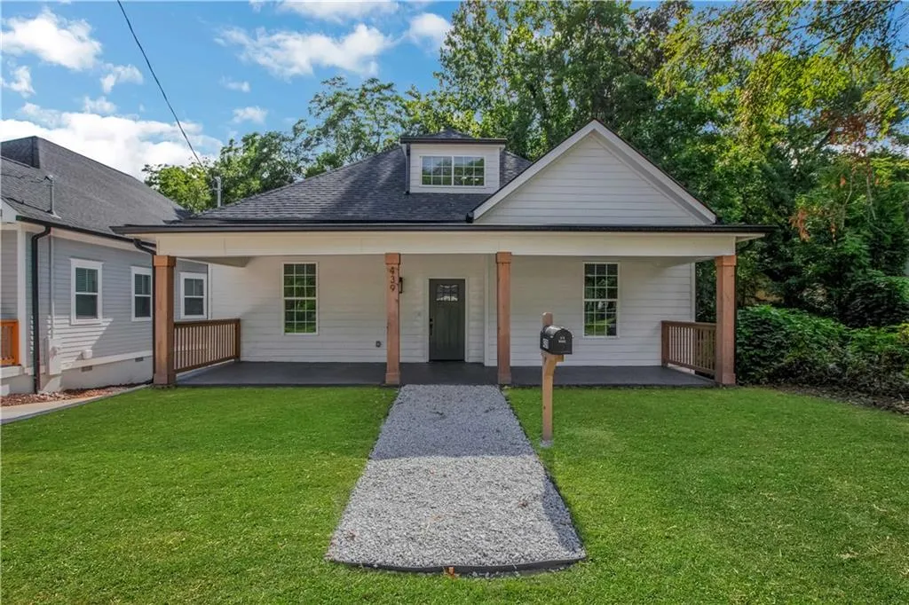 Bungalow-style home with a front lawn, roof with shingles, and covered porch