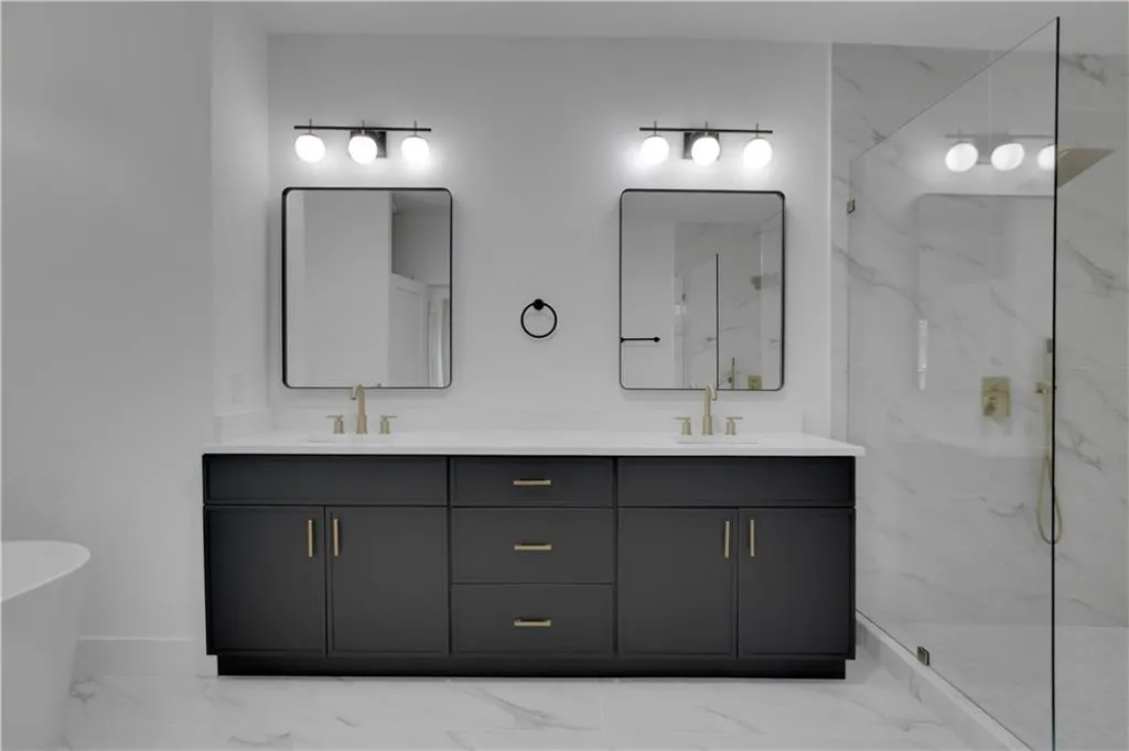 Full bath with light marble finish flooring, double vanity, a soaking tub, and a marble finish shower