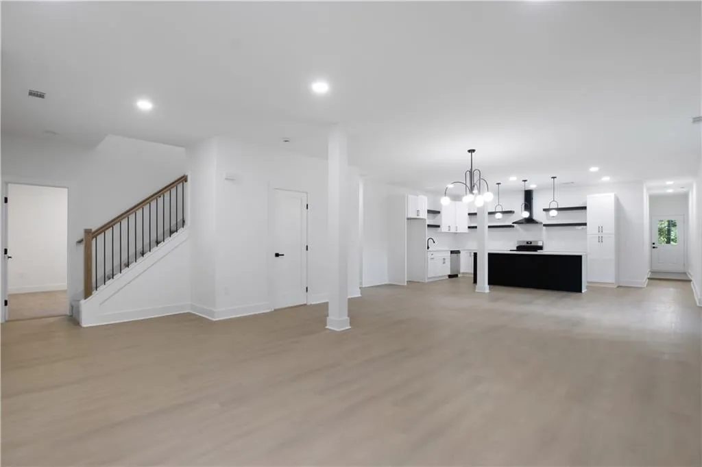 Unfurnished living room featuring recessed lighting, light wood-style floors, a chandelier, and stairs