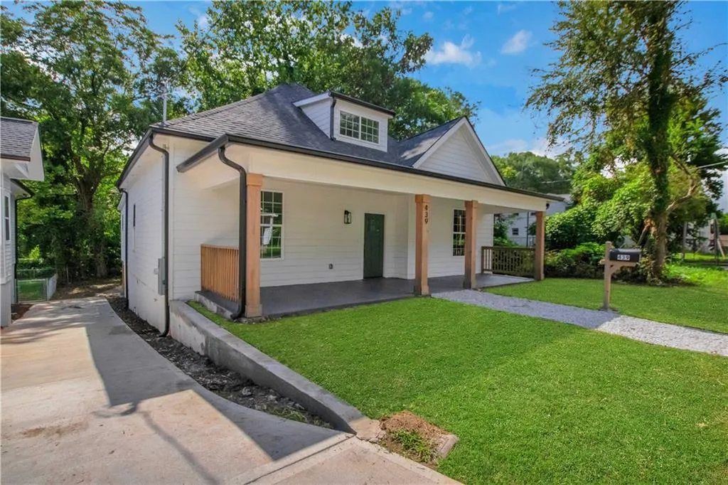 View of front of property with a front yard, a porch, roof with shingles, and concrete driveway