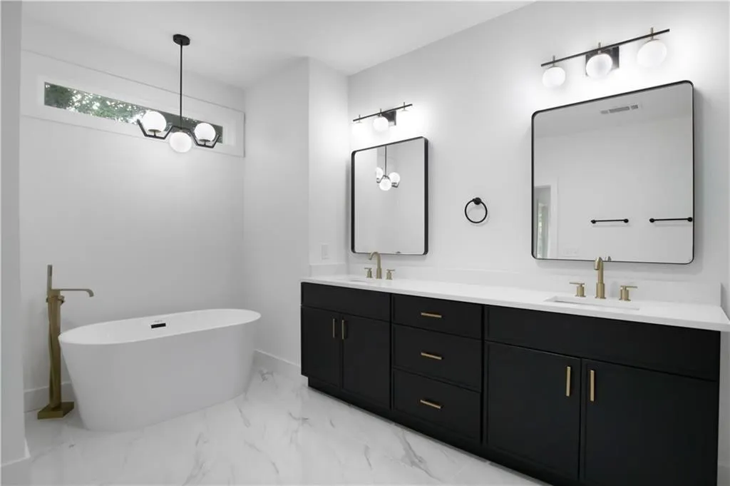 Bathroom featuring double vanity, a freestanding bath, and light marble finish flooring
