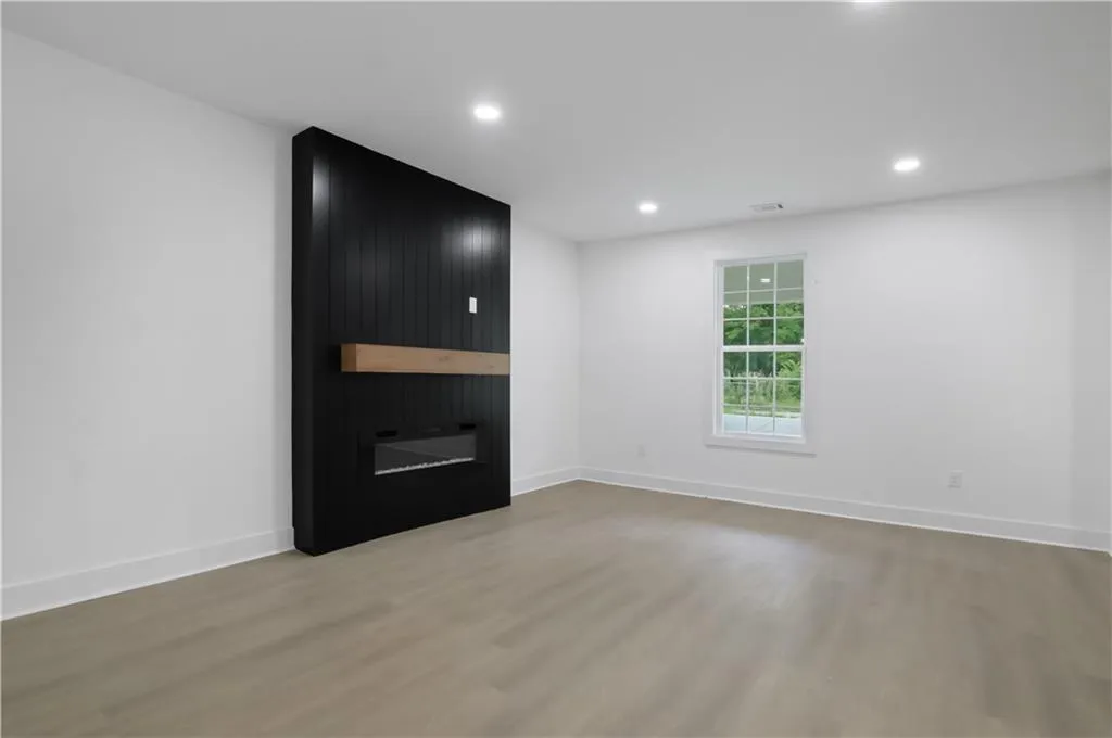 Empty room featuring light wood-type flooring, a large fireplace, and recessed lighting