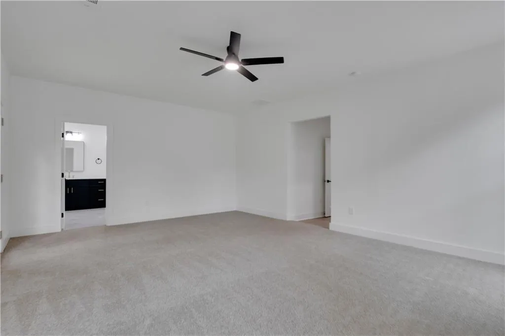 Unfurnished living room featuring light carpet and ceiling fan