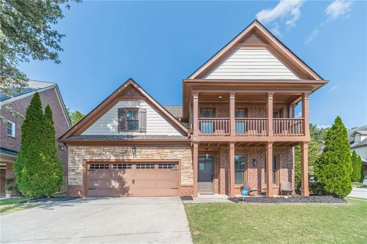 Stone and brick facade with a two-story porch, an attached two-car garage, and a concrete driveway