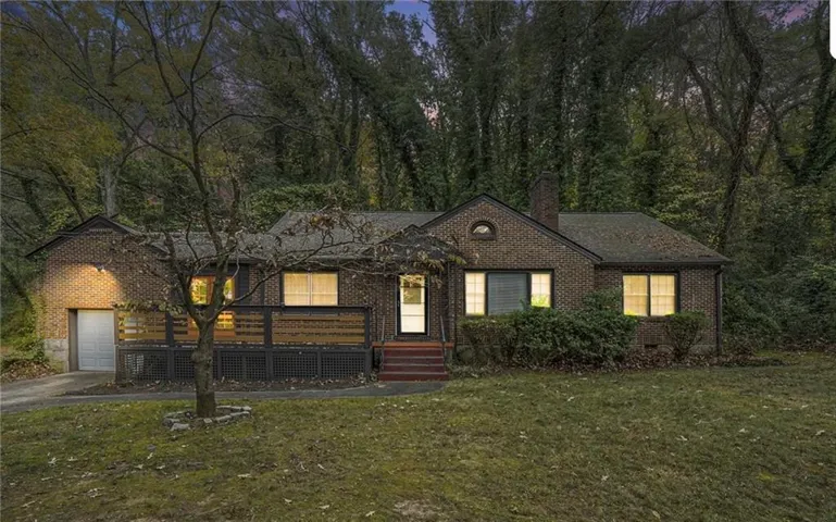 Brick exterior with a prominent chimney, an attached garage, a covered front porch, and a wood-slat privacy fence