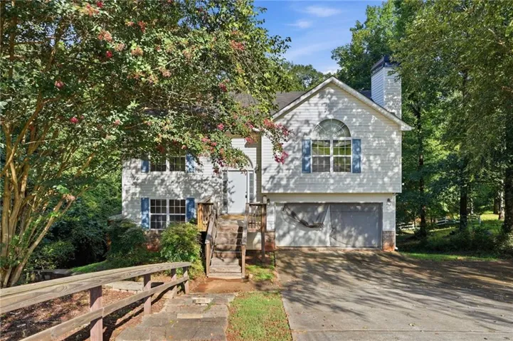 Two-story residence featuring a light-colored exterior with architectural shingles, multi-pane windows, and a chimney