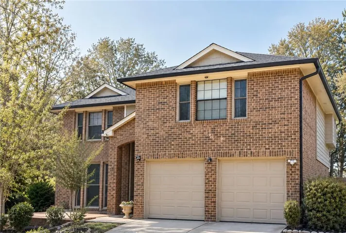 Brick exterior with a prominent two-car garage, dark-framed windows, and a black shingle roof