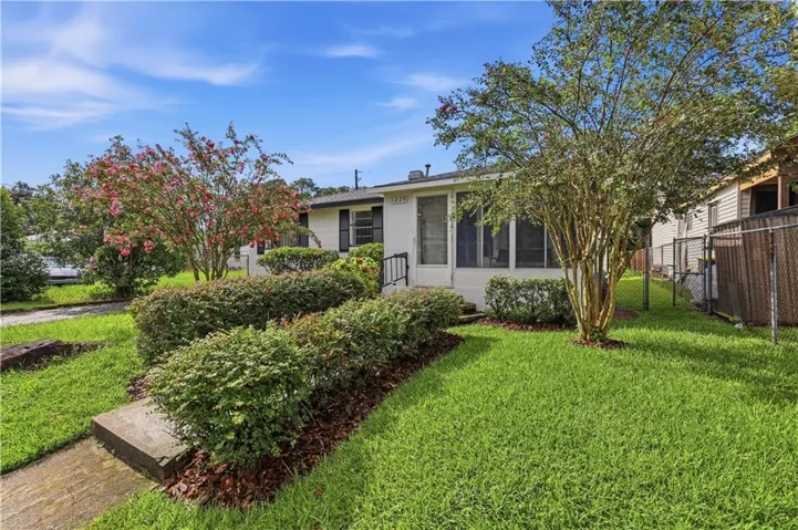 Manicured front lawn with mature landscaping, including flowering trees and hedgerows