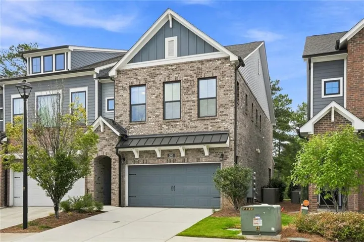 Brick and siding exterior with a pitched roof, featuring a two-car garage with a dark gray door, and a covered entry