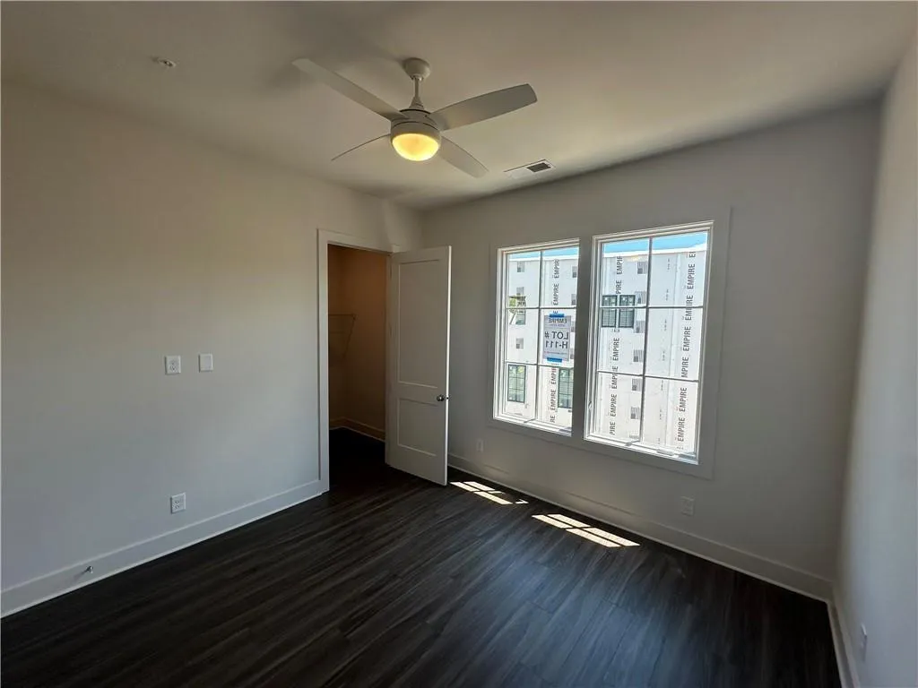 Empty room featuring dark wood-type flooring and ceiling fan