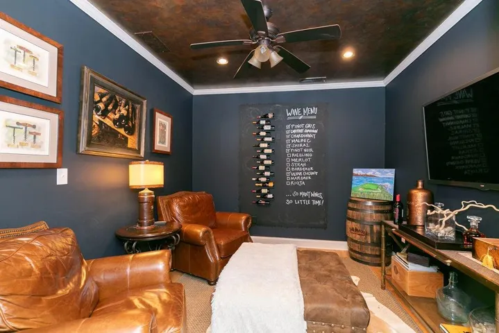 Carpeted living room featuring ceiling fan and crown molding
