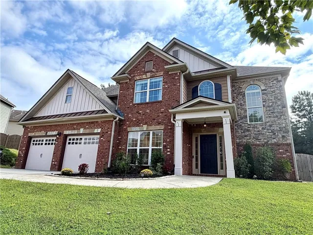 Brick, stone, and board & batten siding exterior with a covered entry, two-car garage, and arched Palladian windows