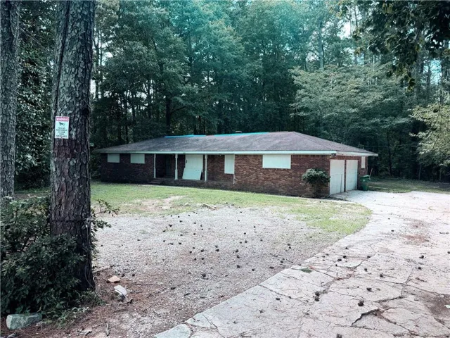 Brick exterior residence featuring a front porch with white columns, a white front door, and a two-car attached garage