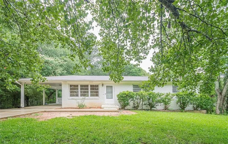 White brick exterior with a single-car carport, covered entry, and front yard