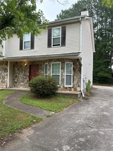 Stone and siding exterior with dark shutters, front entry with transom window, and concrete driveway