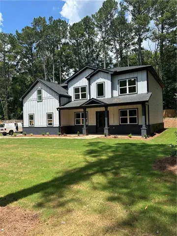 Two-story residence featuring light siding with dark trim, a covered front porch, and a large front lawn