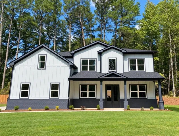 Two-story residence featuring light-colored vertical siding and dark trim