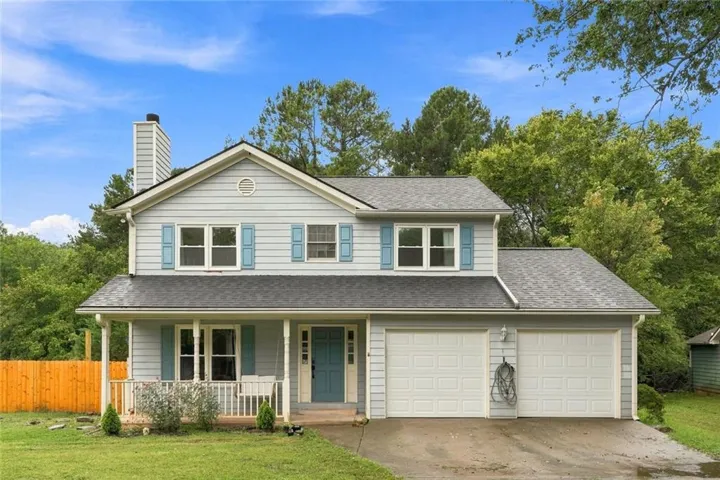 Two-story residence featuring light blue siding, a covered front porch, and a two-car garage with white panel doors