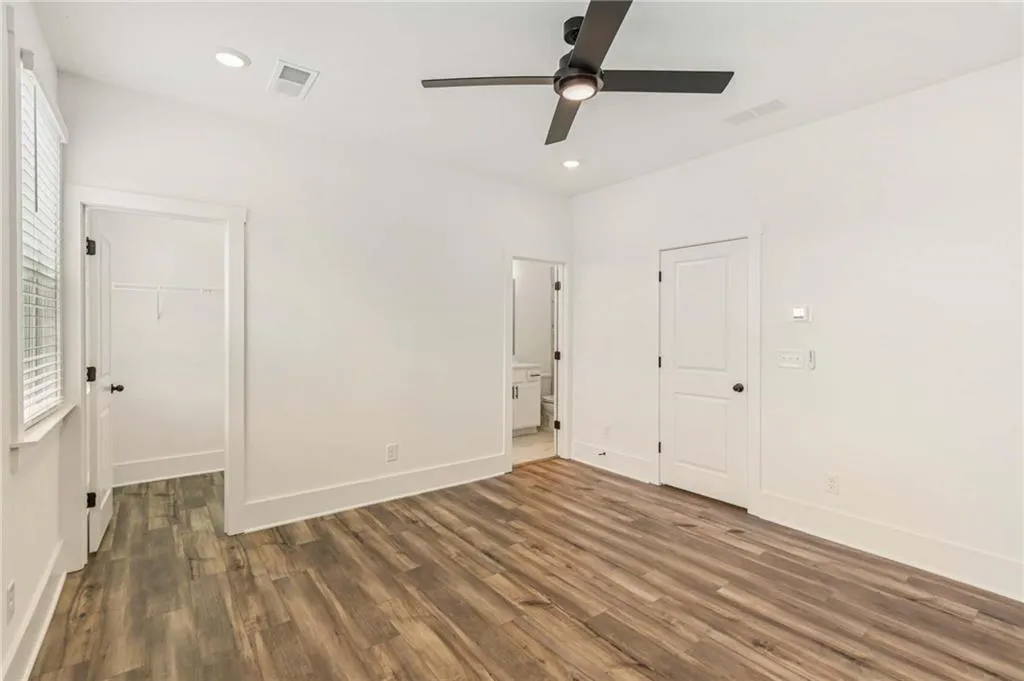 Unfurnished bedroom with wood finished floors, a walk in closet, recessed lighting, a ceiling fan, and a closet