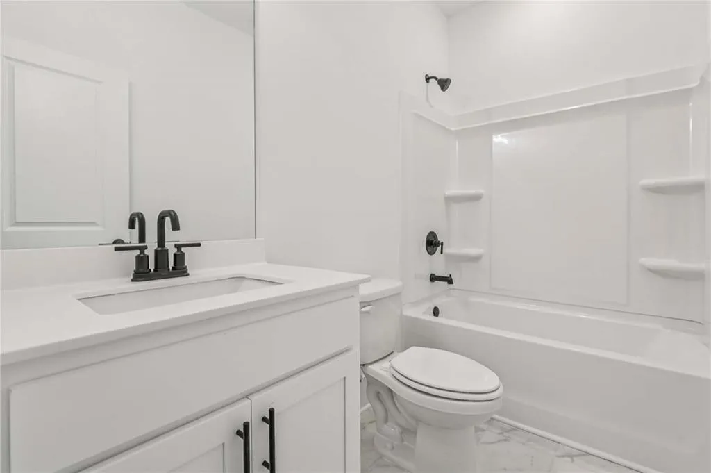 Bathroom featuring marble look tiles, vanity, and bathing tub / shower combination