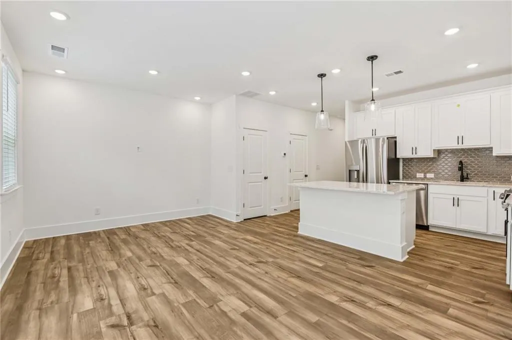 Kitchen with appliances with stainless steel finishes, a kitchen island, backsplash, light wood finished floors, and recessed lighting