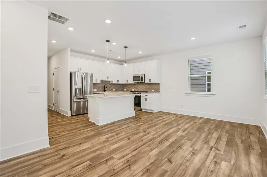Kitchen featuring appliances with stainless steel finishes, white cabinetry, a center island, tasteful backsplash, and light countertops