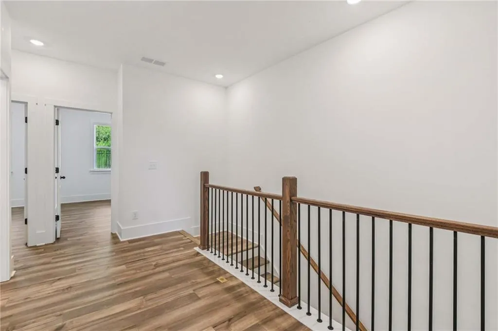 Hallway featuring an upstairs landing, wood finished floors, and recessed lighting