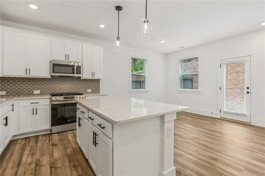 Kitchen with appliances with stainless steel finishes, wood finished floors, backsplash, a center island, and recessed lighting