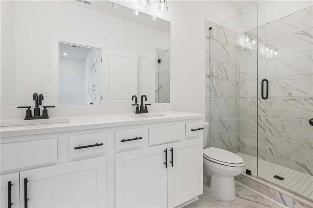 Full bathroom featuring marble finish flooring, a marble finish shower, and double vanity