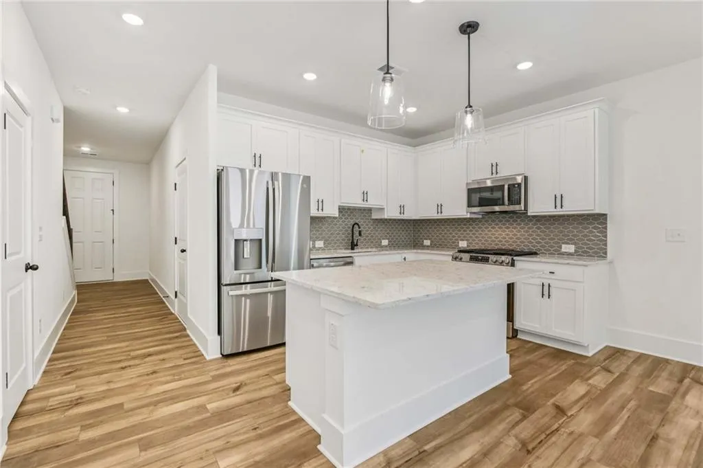 Kitchen with appliances with stainless steel finishes, light wood-type flooring, tasteful backsplash, white cabinets, and recessed lighting